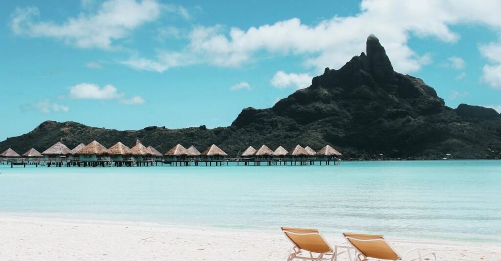 Pristine beach with loungers facing turquoise waters and iconic Mount Otemanu in French Polynesia.