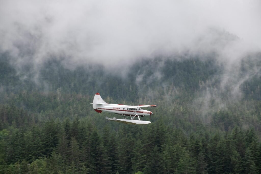 A seaplane flying over a misty forest with fog rolling over the mountains, capturing a scenic adventure mood.
